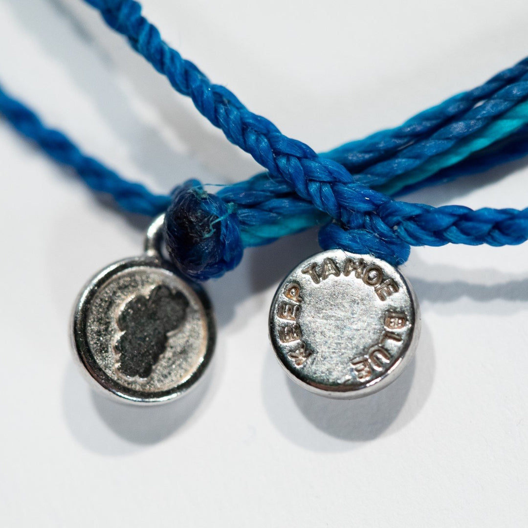 close up of Keep Tahoe Blue charm on Pura Vida string bracelets 