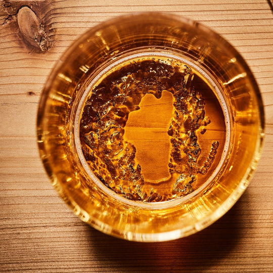 aerial view of filled pint glass featuring Lake Tahoe region molded into the base on wooden table